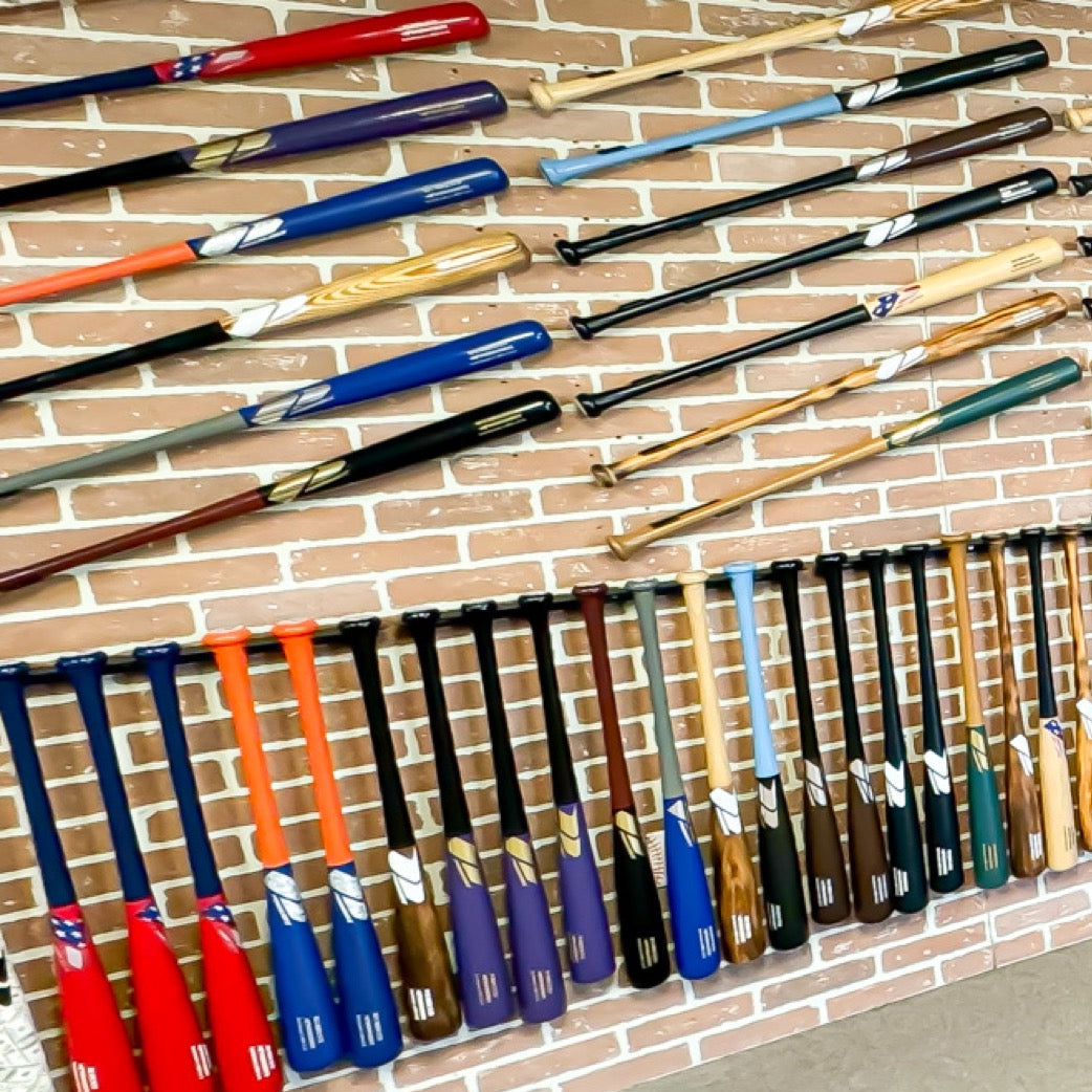 Phoenix Bats showroom display featuring wood bats arranged on HIDEit Horizontal Bat Mounts and 8Bat holders for a pro shop–style retail wall fixture.