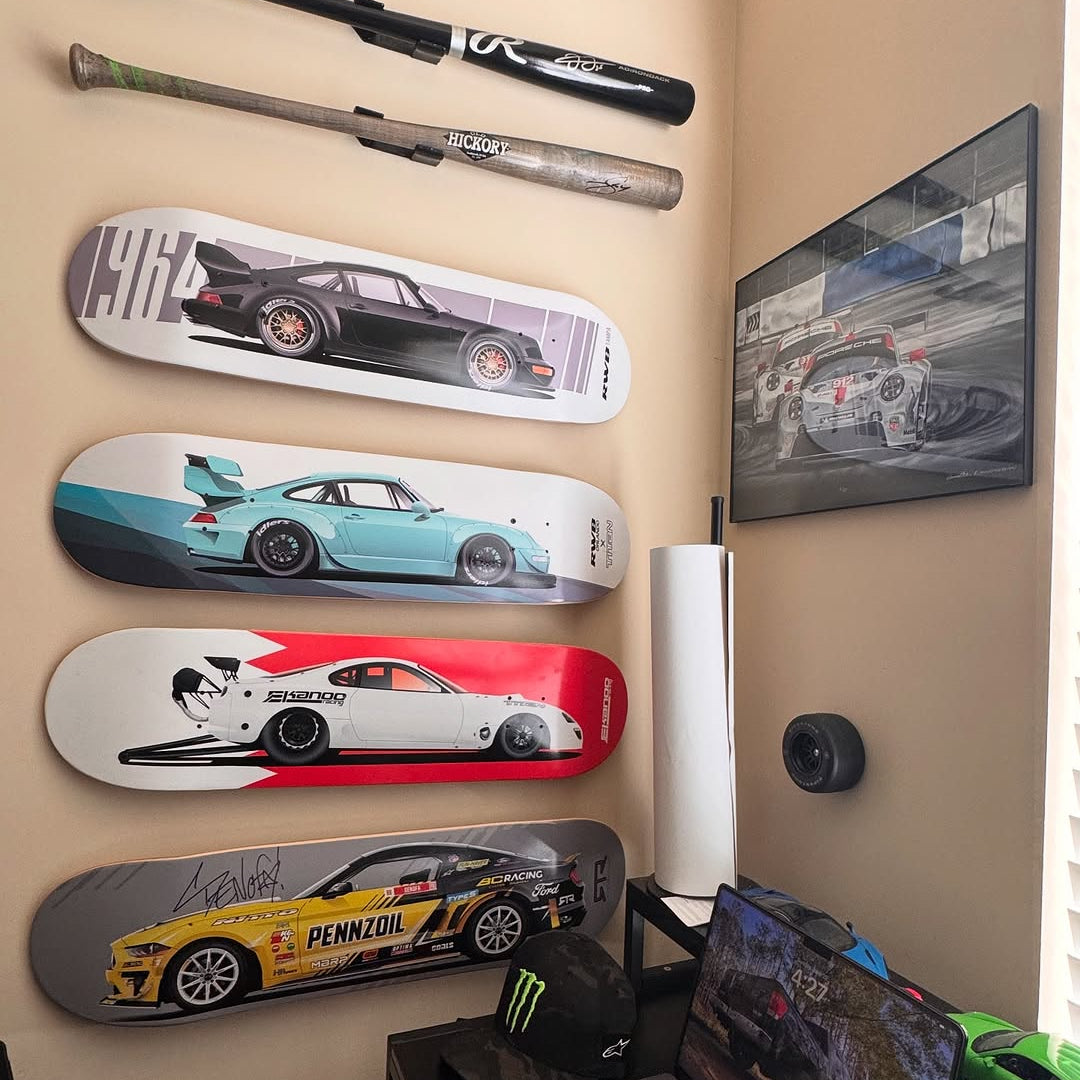 c12productions’ corner desk setup with car-themed skateboard decks mounted on HIDEit Deck Mounts and baseball bats displayed in HBat wall mounts for a collector-style feature wall.