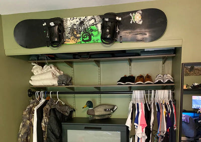 Gabe's afterHIDEit bedroom setup featuring a hunting-themed closet and a snowboard displayed above the wardrobe using the HIDEit HBoard wall mount for organized gear storage.
