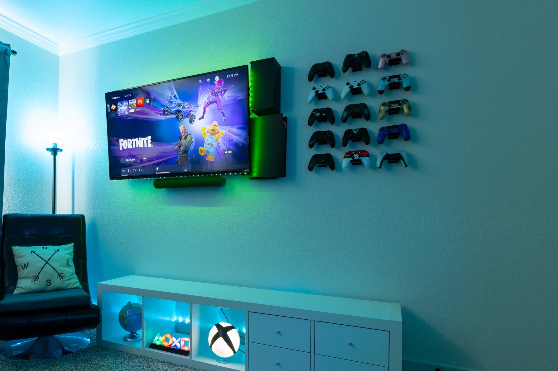 Gamer room with consoles mounted beside the TV and a wall of mounted controllers